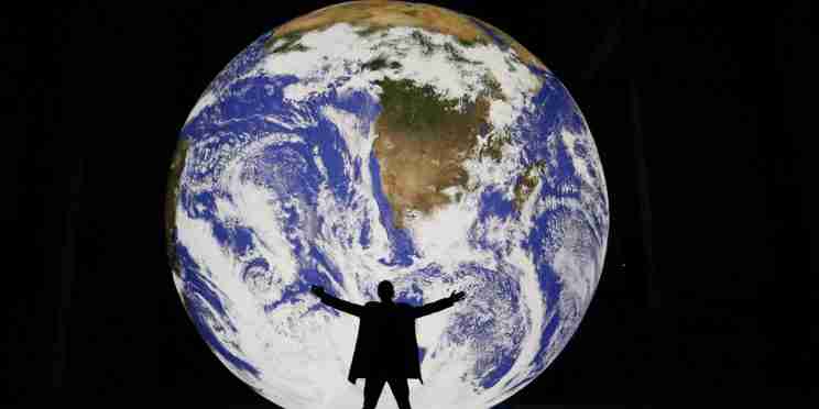 Man silhouetted in front of large lit up globe