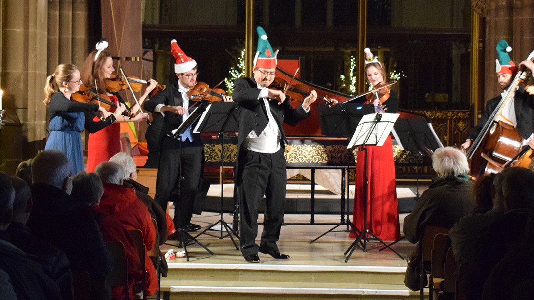 Musicians playing classical instruments in Christmas hats