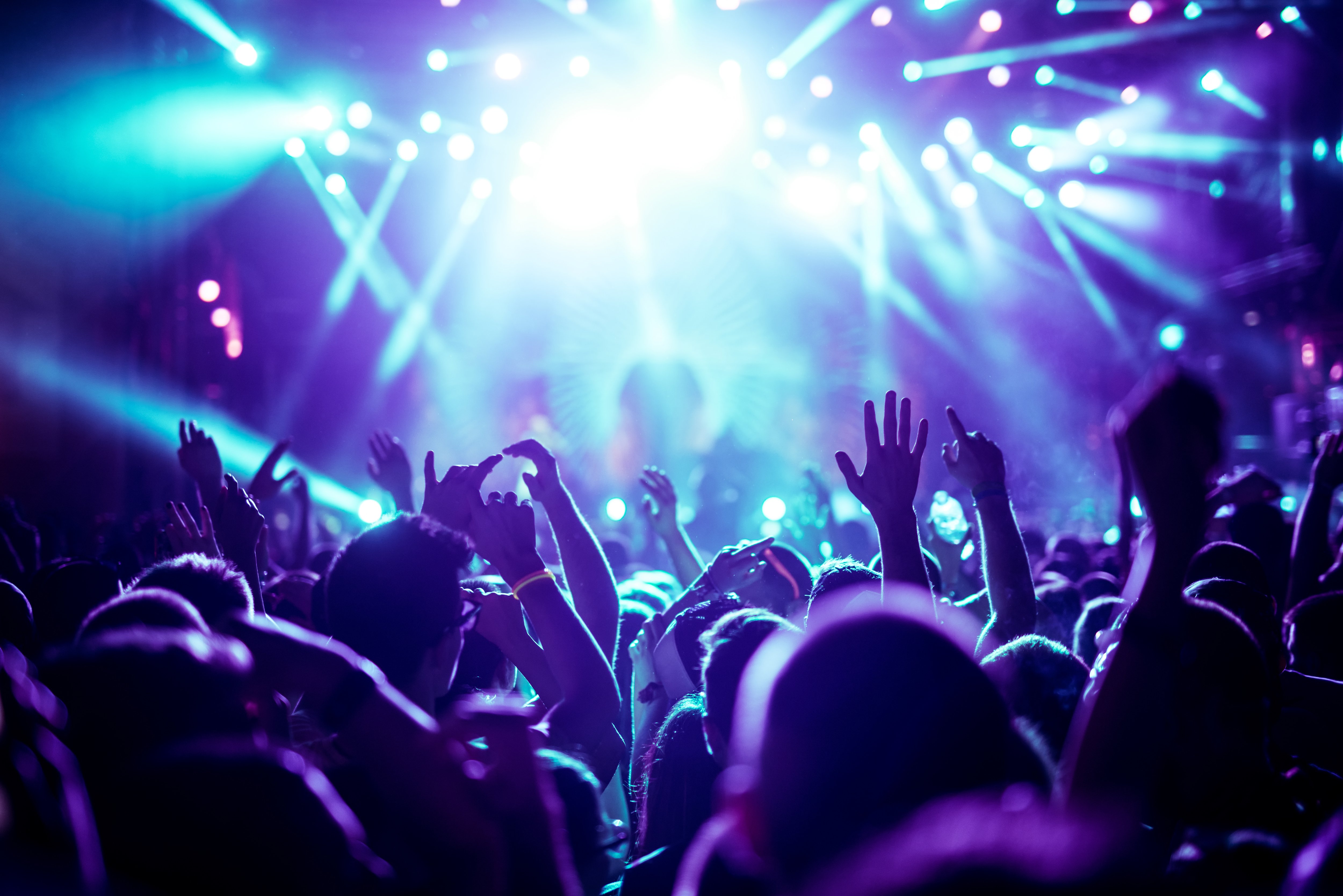 A gathering of people facing a stage with bright lights